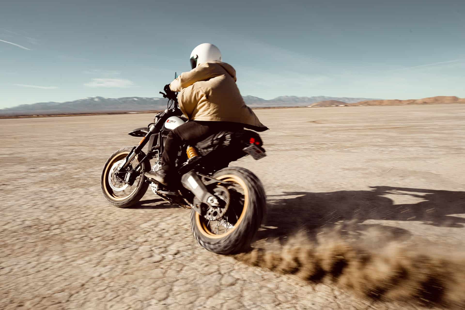 Motorcyclist speeding across a flat, arid landscape, an amazing guide for outdoor enthusiasts.