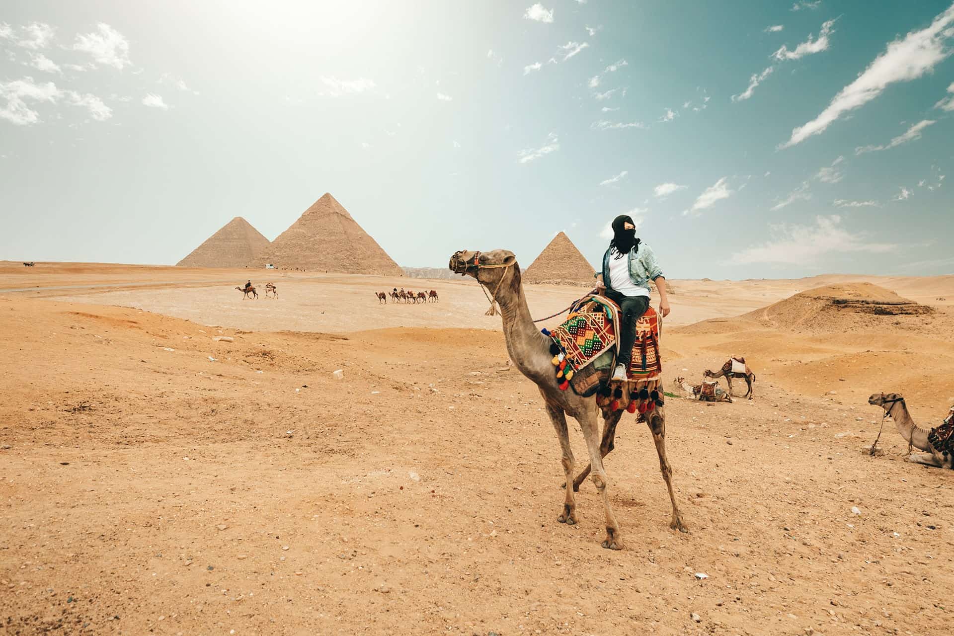 Tourist riding a camel near the pyramids in the desert on their first solo trip.